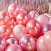 A close-up of pink and iridescent latex balloons arranged for party decorations.