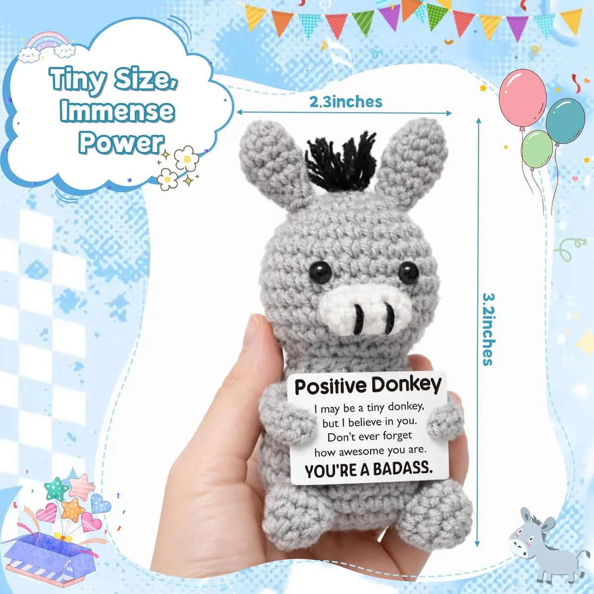 A handmade crochet positive donkey ornament in gray is held in a hand against a light blue background.