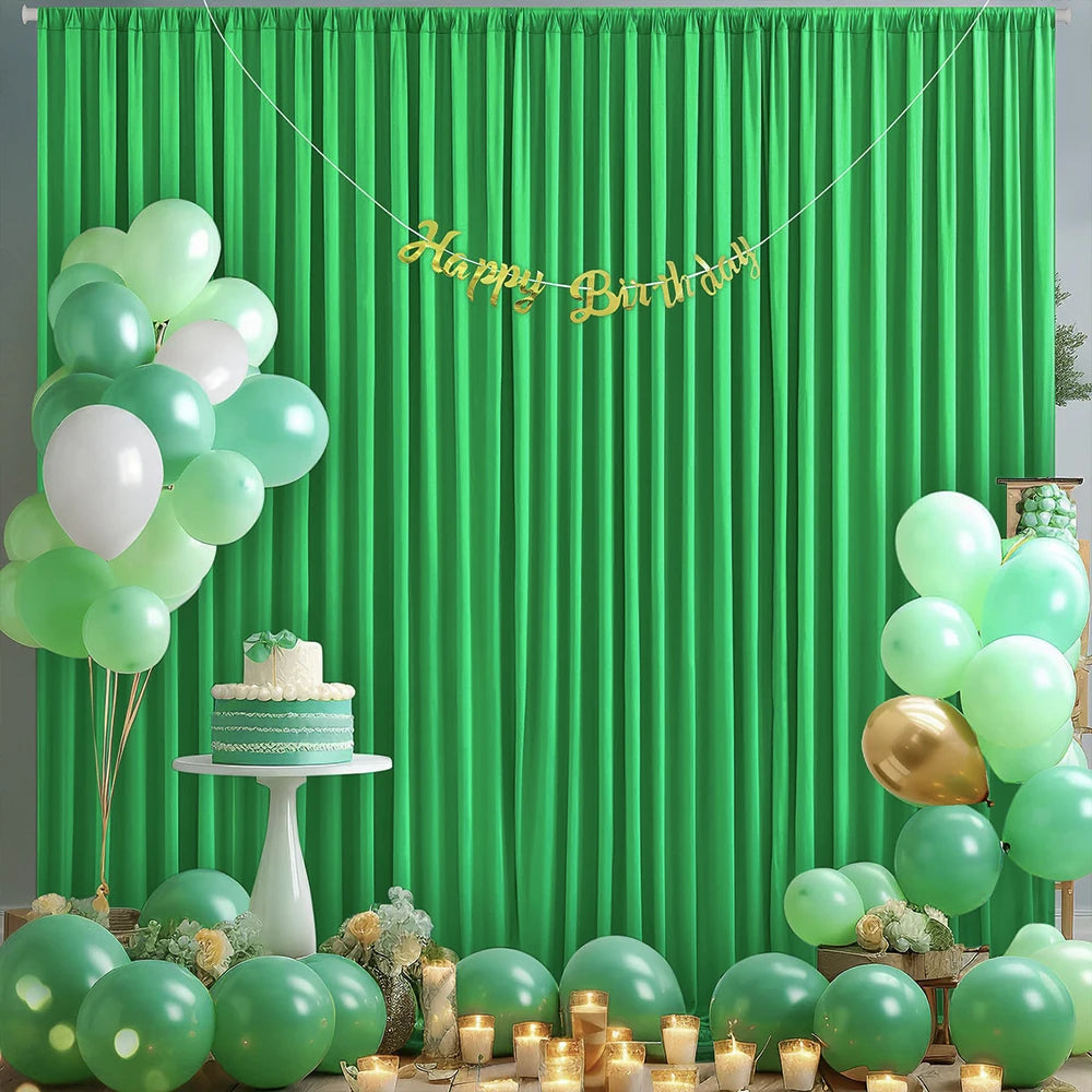A green curtain backdrop decorated with balloons and a gold birthday banner for a celebration.
