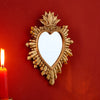 A golden flame sacred heart wall pendant with a resin finish mounted on a red wall.