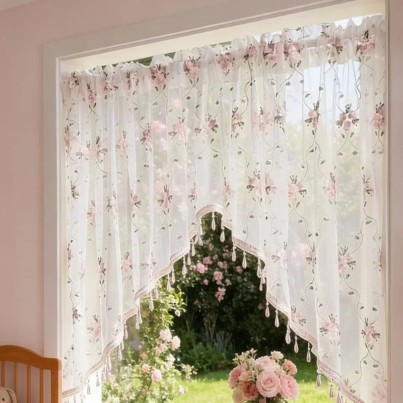 Elegante Dreieckspfenn-Vorhang mit rosa Blumenstickerei hängt im Fenster.