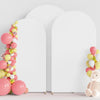 A white wedding arch cover decorated with pink and yellow balloons and a pink teddy bear.