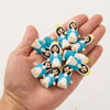 A hand holds several small resin statues of the Virgin Mary figures in blue and white.
