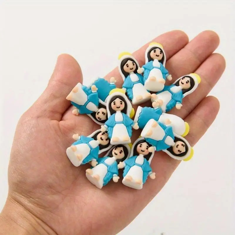 A hand holds several small resin statues of the Virgin Mary figures in blue and white.