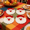 A set of handmade crochet Santa Claus coasters with white and red detailing arranged on a colorful tablecloth.