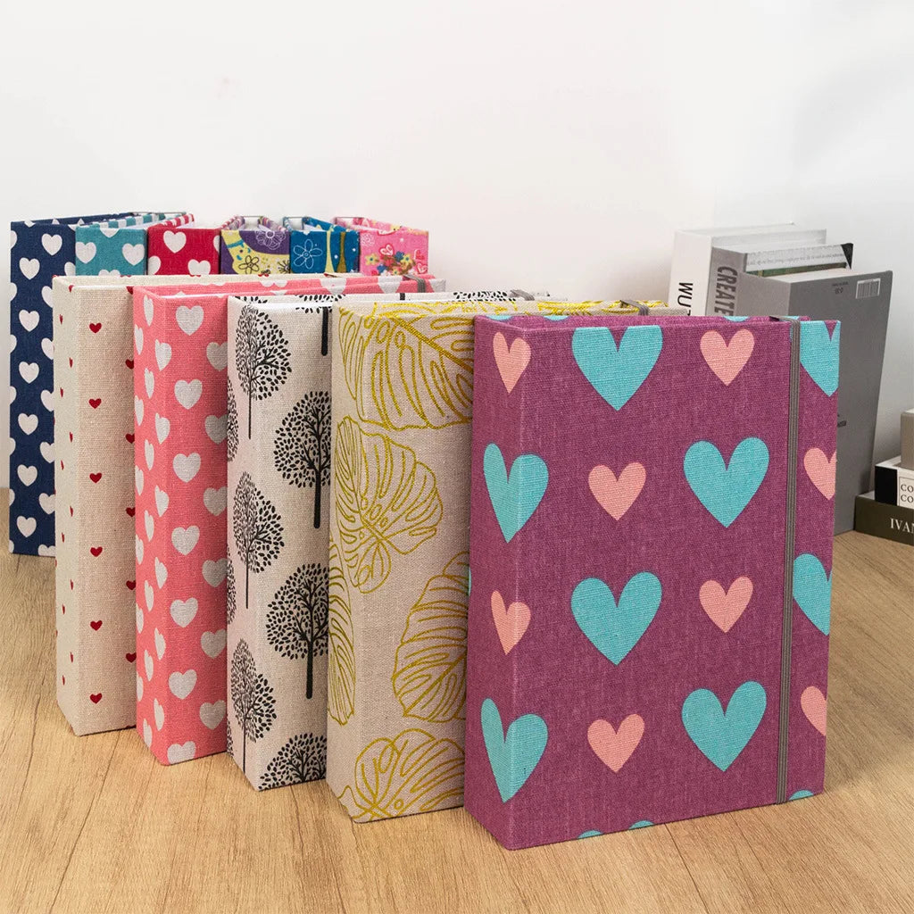 A collection of linen printed photo albums in various colors and designs, including pink, green, purple, and blue.