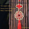 Antique copper five emperor coin pendant with a red Chinese knot hanging from a bamboo rod.