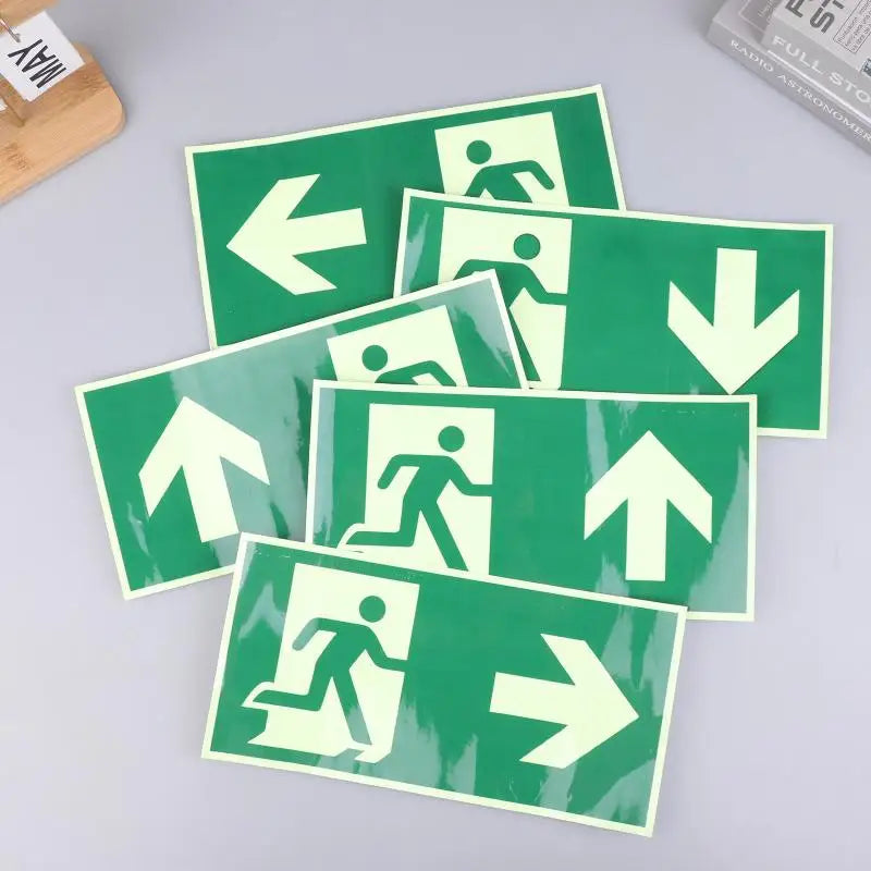 A collection of photoluminescent emergency exit sign decals showing various directional arrows on a green background.