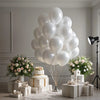 A large bouquet of pearl white latex balloons arranged in a pyramid on a white surface.