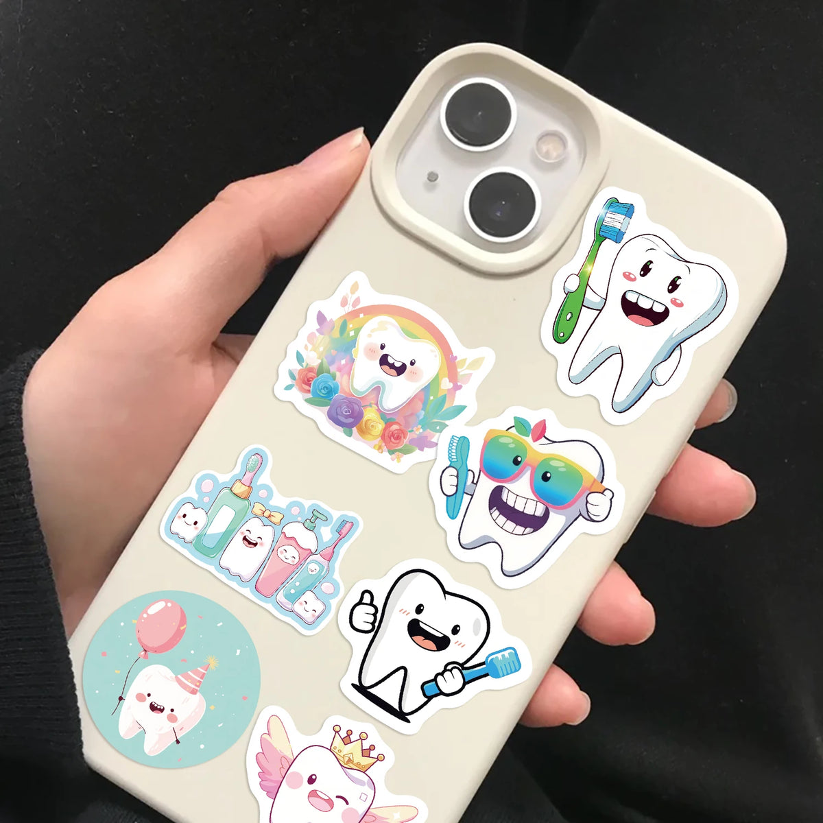 A hand holds a phone displaying various cartoon tooth fairy stickers on the back cover.