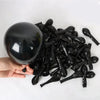 A hand holds a black football balloon party set with number foils, showing many small black balloons.