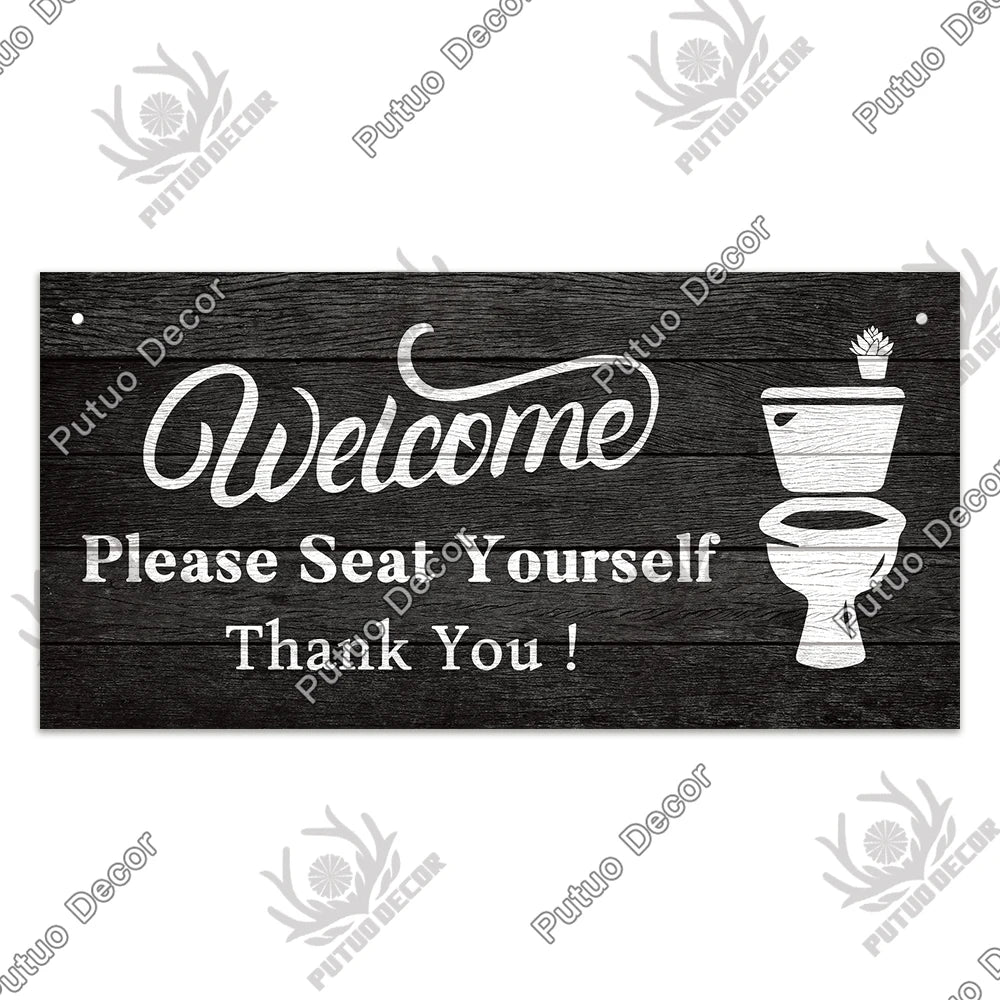 A rustic wooden wall sign with white text that reads Welcome Please Seat Yourself Thank You and features a toilet silhouette.