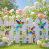 Colorful metal hummingbird wall art featuring vibrant iridescent feathers displayed on a white picket fence with pink and whi