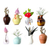 A collection of eight magnetic mini ceramic vases in various colors and shapes holding dried floral arrangements.
