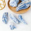 Blue kyanite healing crystal stones on a wooden plate and white background