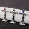 Three ornate metal crucifix desk crosses with self-adhesive bases displayed on a dark surface.