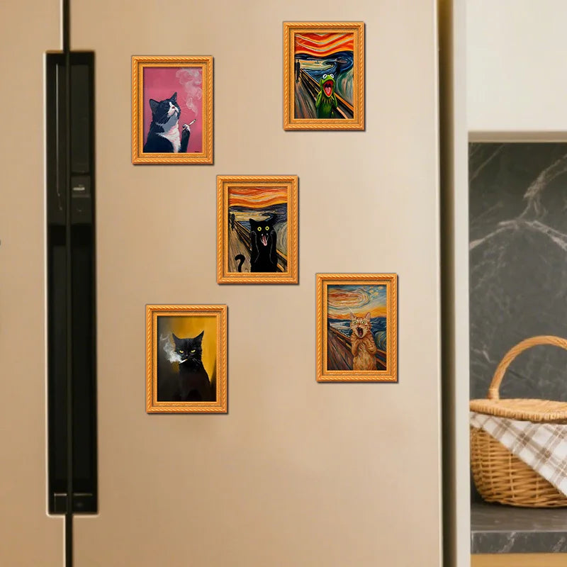 A display of five framed pictures featuring cats in various artistic styles mounted on a light wall.