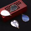 A set of natural agate and rose quartz pendant charms displayed inside a wooden box with a geometric pattern.