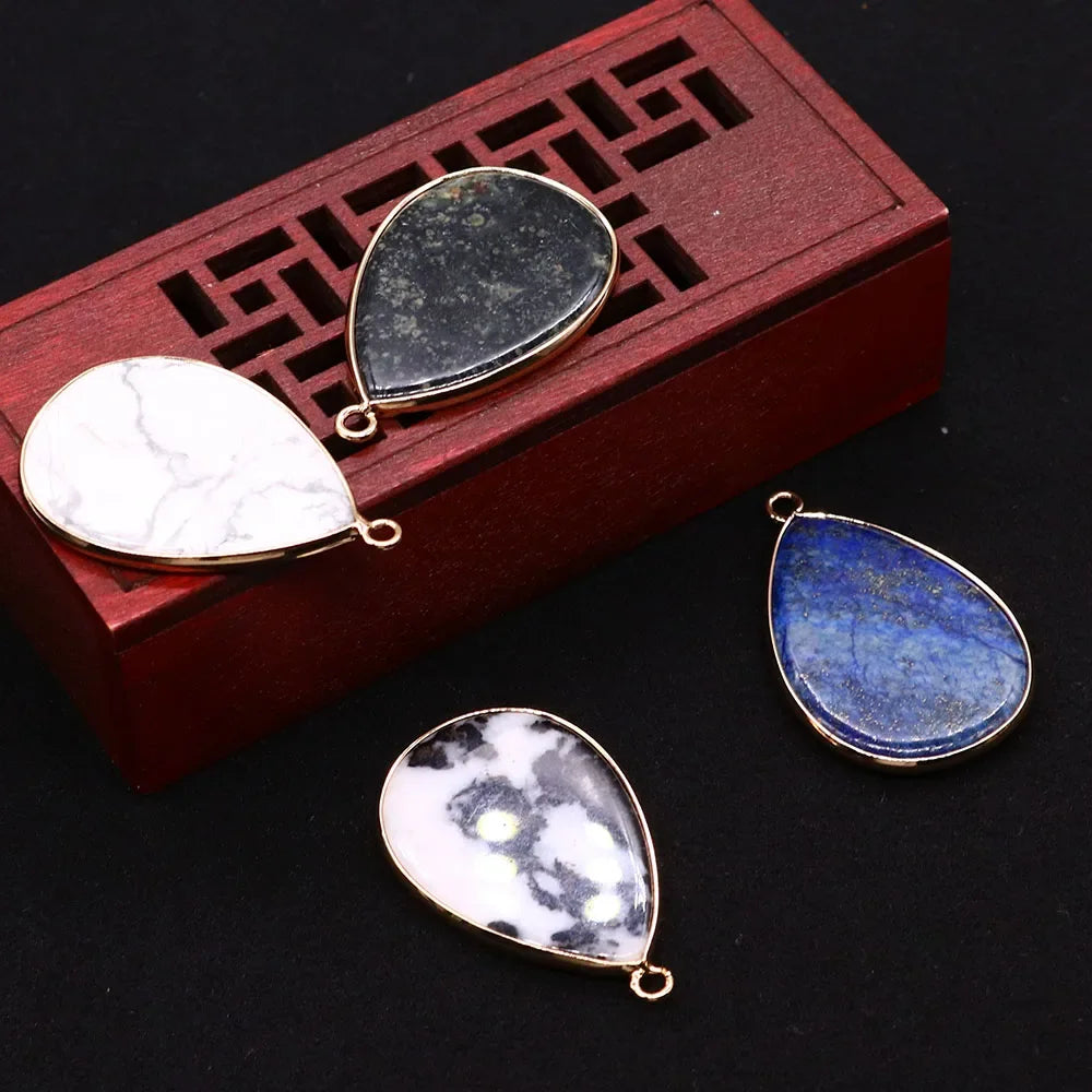 A set of natural agate and rose quartz pendant charms displayed inside a wooden box with a geometric pattern.