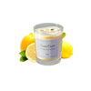 A glass jar of scented candle with a yellow wax and lemon slices beside it.