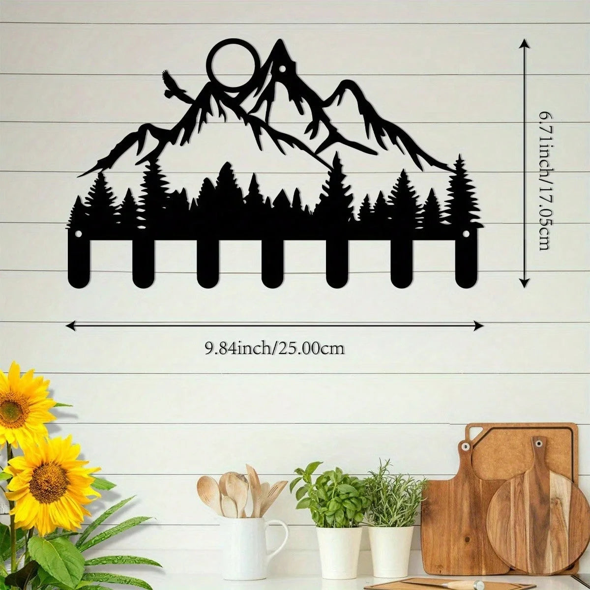 Black silhouette of mountains and trees on a white wall with measurements.