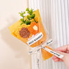 A bouquet of handmade crochet flowers in orange and yellow velvet blooms wrapped in sheer cellophane for gifting