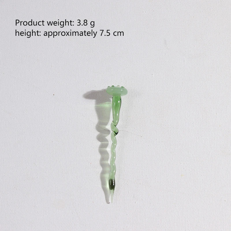 A small, translucent green glass flower bouquet with a stem and leaves.