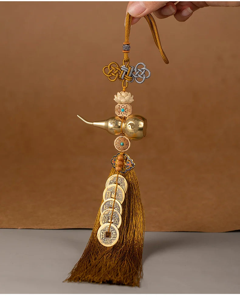 A brass gourd and five emperor coins hanging ornament with a golden thread and tassel.