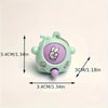 A small, light green keychain shaped like a face with a purple rock-paper-scissors symbol on it.