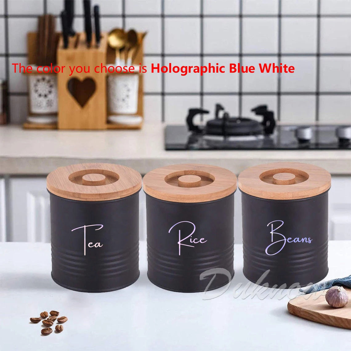 Three black canisters with wooden lids labeled Tea, Rice, and Beans on a white surface.