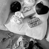 A collection of black and white accessories including handbags, jewelry, and high heels displayed on a light sofa.