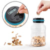 A hand is using a coin to measure the amount in a transparent piggy bank filled with gold coins.