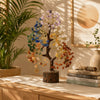 A small crystal tree ornament featuring blue and yellow floral elements displayed on a wooden surface.