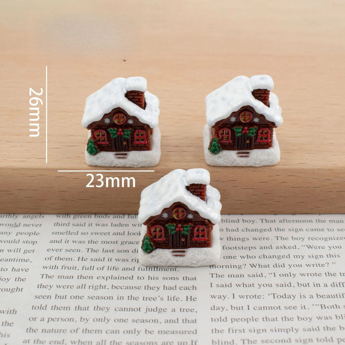A set of festive Christmas resin decor featuring miniature houses with snow and greenery.