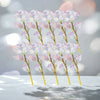 A display of delicate, translucent pink and purple artificial crystal flowers on thin gold stems.