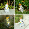 A white rabbit garden statue with a butterfly light is placed on a stone surface surrounded by green foliage.