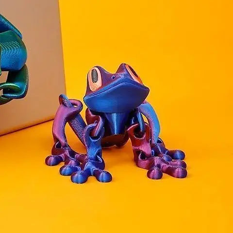A blue tree frog ornament with purple limbs is displayed against a bright yellow background.