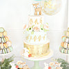 A tiered cake decorated with gold and pale green accents featuring a fox figurine and floral elements.