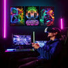 Three framed canvas prints featuring retro gaming themes and neon lighting displayed on a dark desk setup.