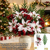 A festive bouquet of red and white artificial flowers and greenery displayed in a white vase.
