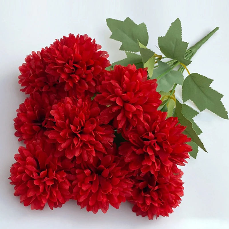 A bouquet of artificial red hydrangeas and green camellia leaves.