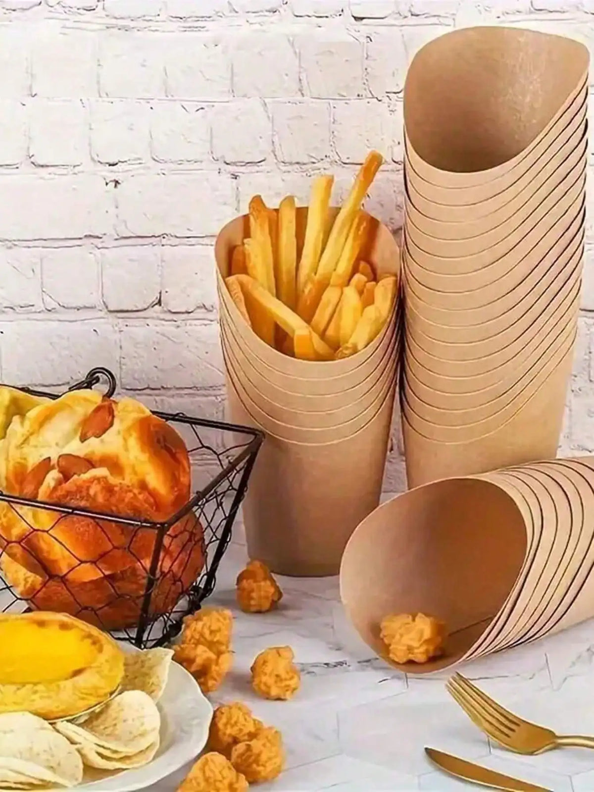 A collection of disposable kraft paper serving cups, french fries, bread, and chips arranged on a white surface.