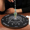 A crystal pendulum hanging from a silver chain rests on a wooden board for dowsing and divination.