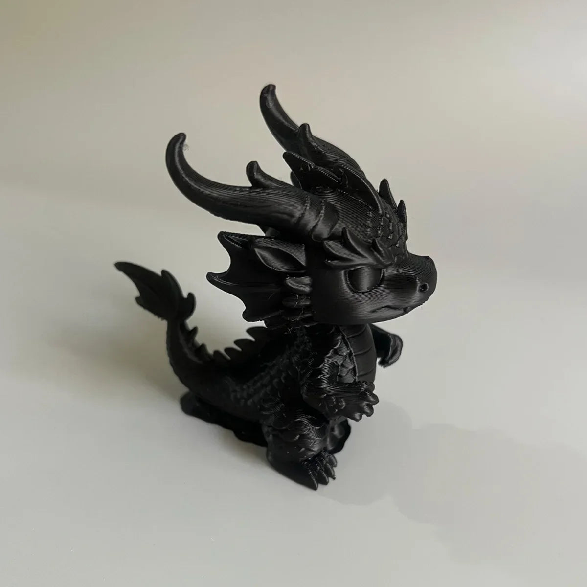 A black miniature dragon desk ornament with spiky horns and detailed scales.