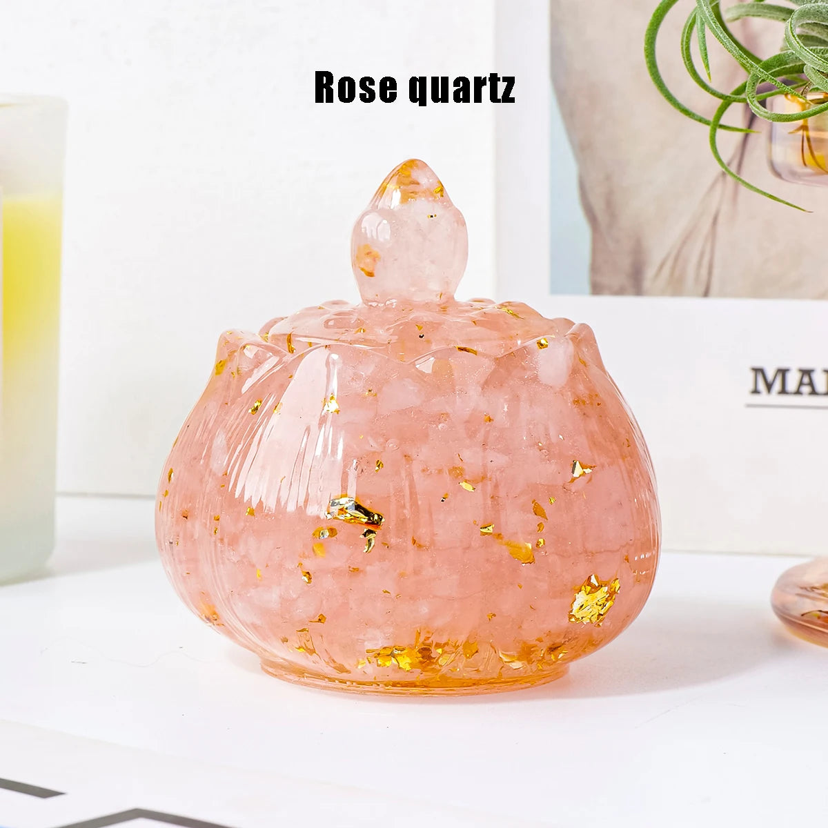 A smooth, translucent rose quartz bowl with a pointed top and gold flecks, displayed on a white surface.