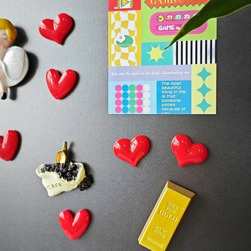A collection of red heart-shaped fridge magnets and a colorful game card featuring a yellow star.