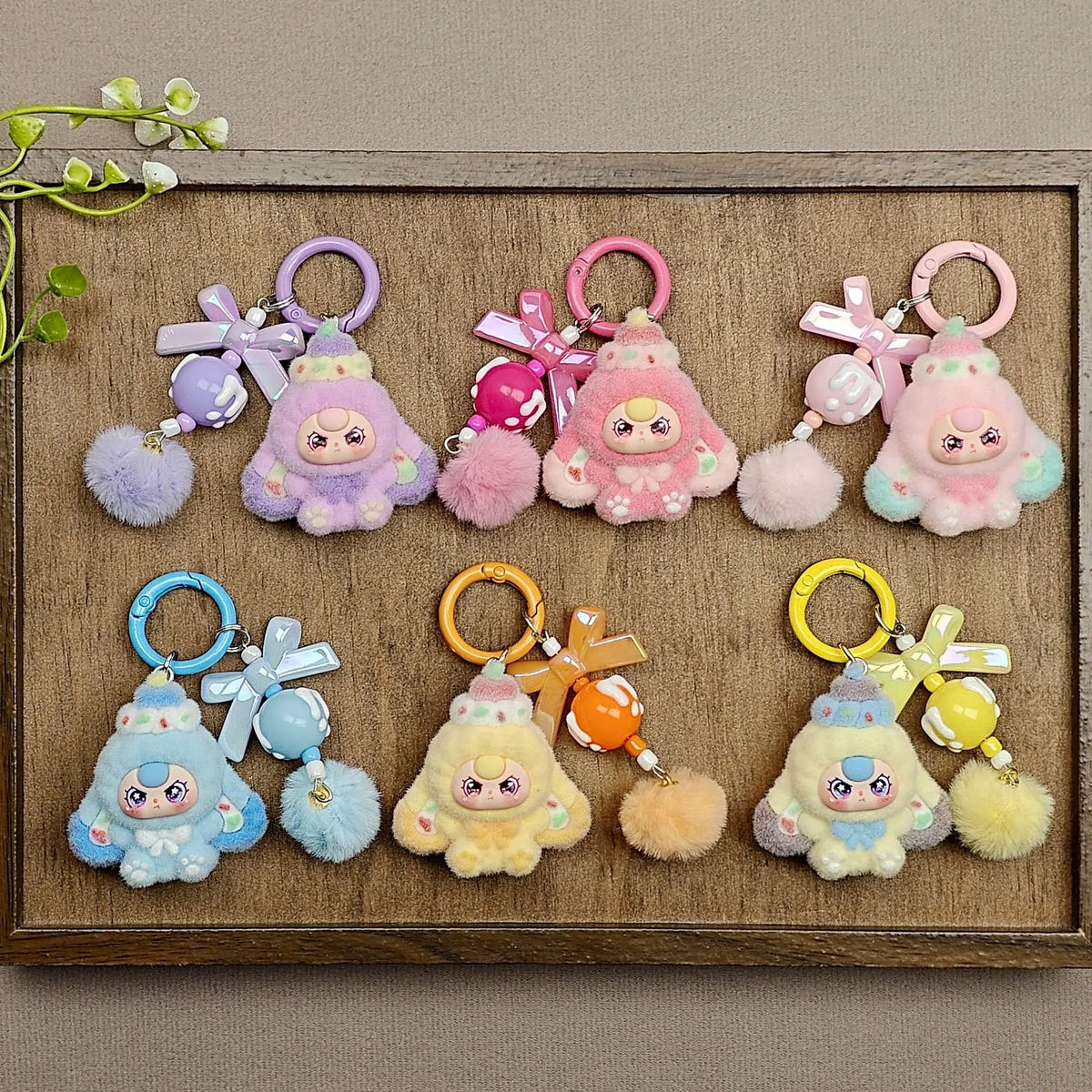 A collection of cute heart plush keychain charms in various pastel colors and textures displayed in a wooden frame.