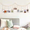 A photo display garland featuring small framed photos suspended from a string against a white wall.