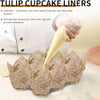 A hand is holding a yellow tulip cupcake liner, with several brown newspaper style liners laid out on a white surface.