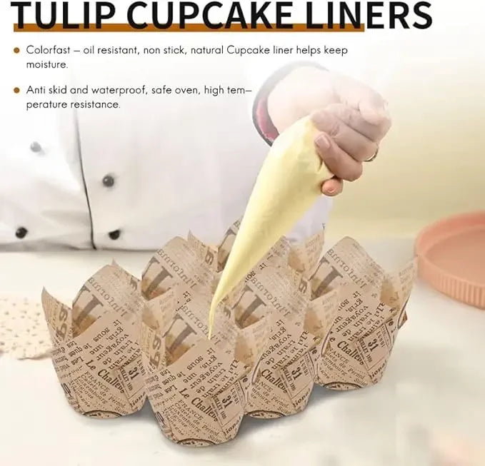 A hand is holding a yellow tulip cupcake liner, with several brown newspaper style liners laid out on a white surface.